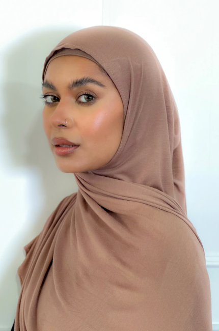 Woman wearing a brown Jersey hijab against a white background