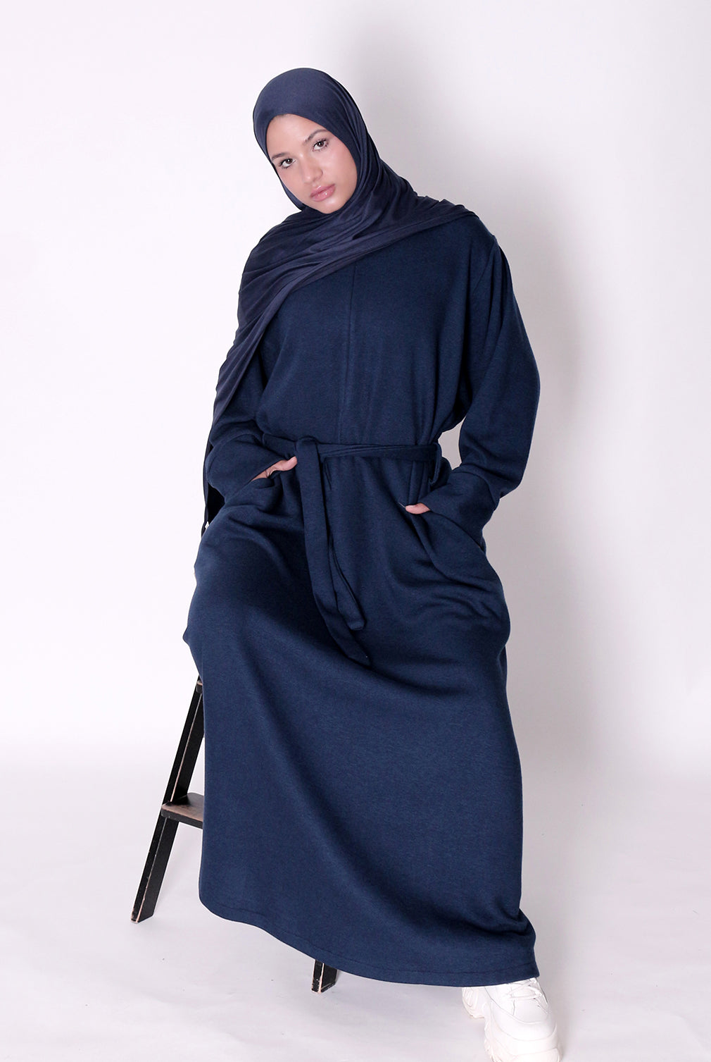 Woman wearing a navy blue abaya and hijab on a white background