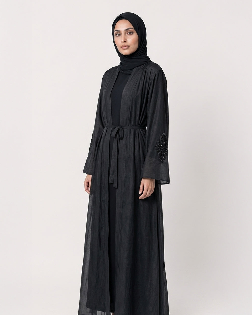 Black silk cotton Persia jacket with handcrafted embellishment, worn open over a matching black slip dress.
