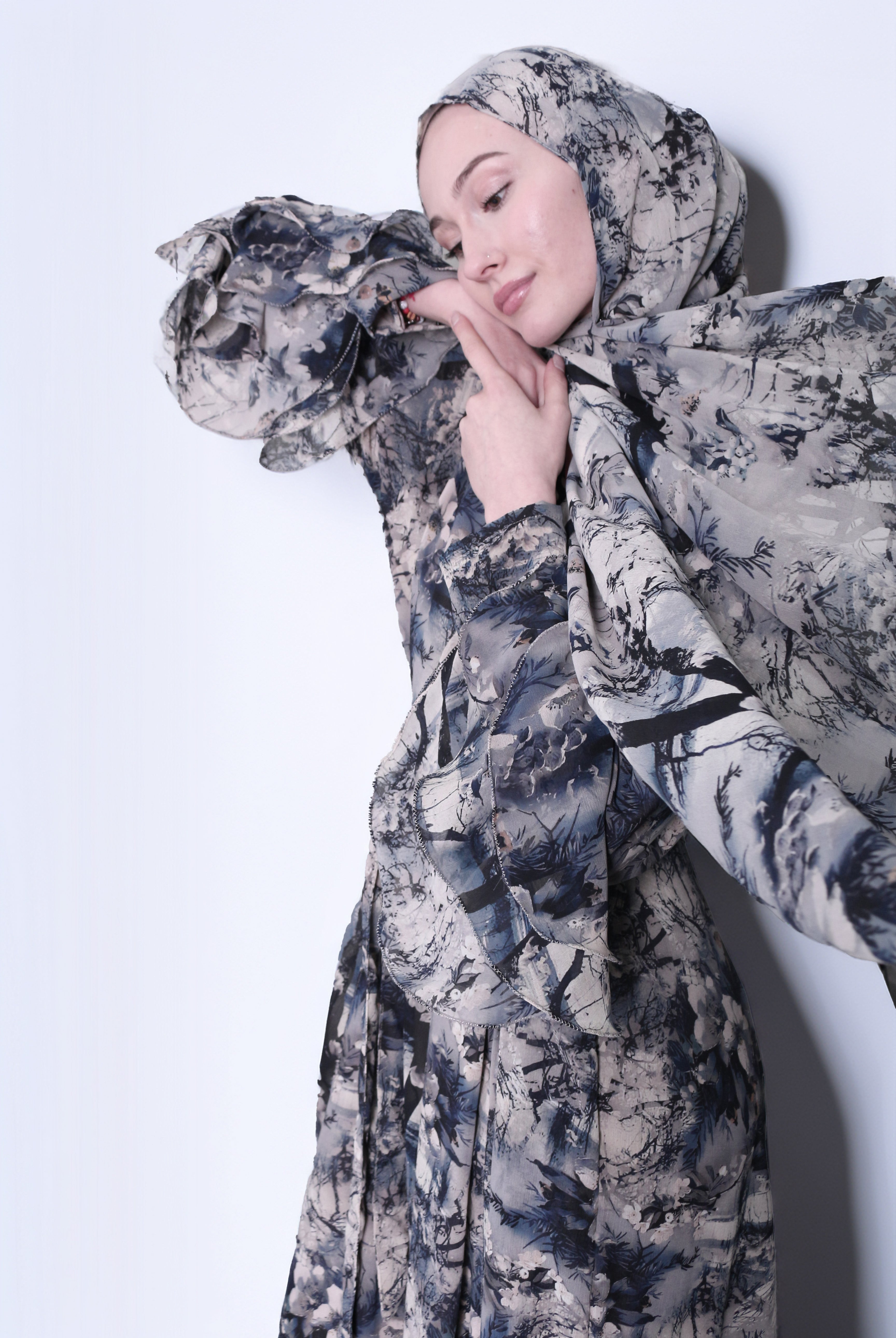 A woman wearing a Kyoto print hijab with a floral pattern in shades of gray and blue.