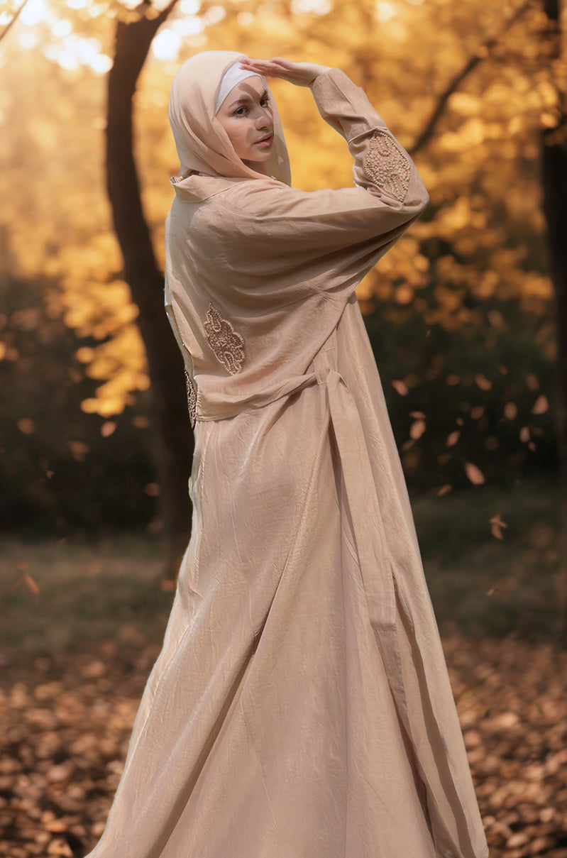 Woman in a beige Maxi Jacket with beaded embroidery standing in a Park during autumn.