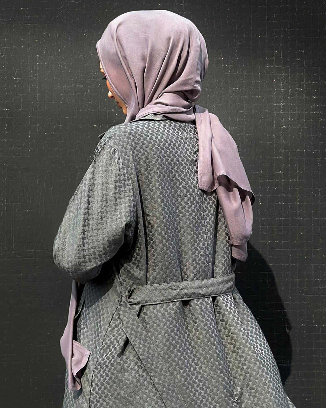 Person wearing a khafiyah coat and maxi jersey hijab against a dark background