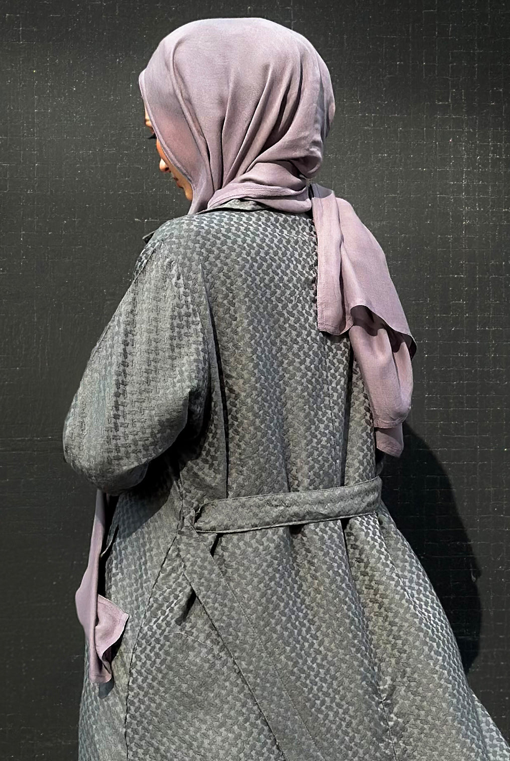 Person wearing a khafiyah coat and maxi jersey hijab against a dark background