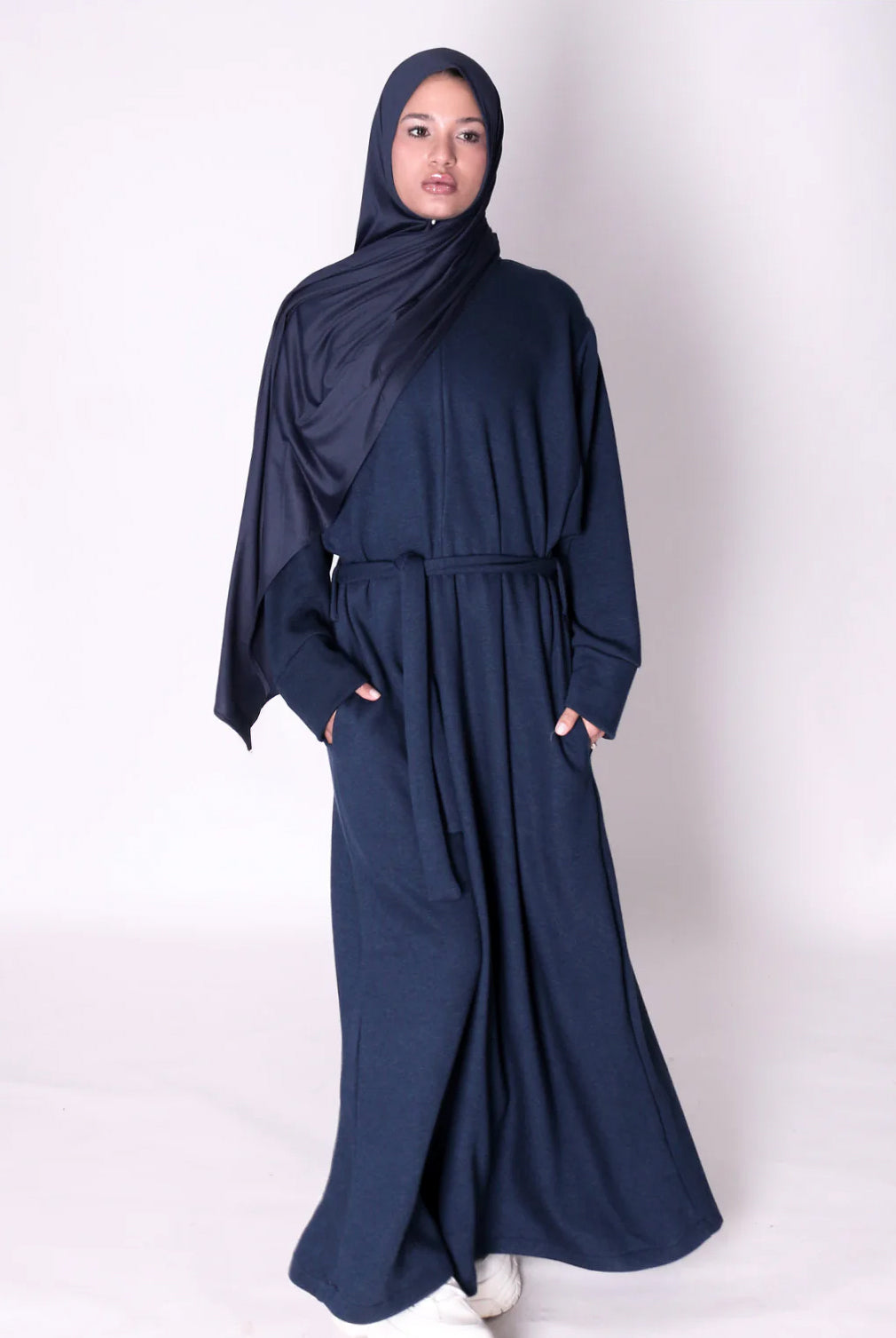 Woman wearing a navy blue abaya dress on a white background