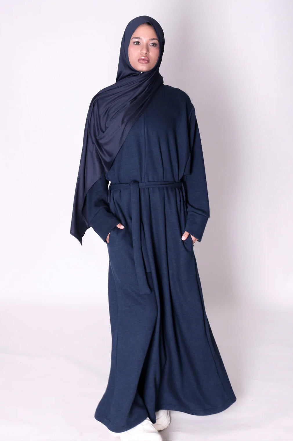 Woman wearing a navy blue abaya dress on a white background