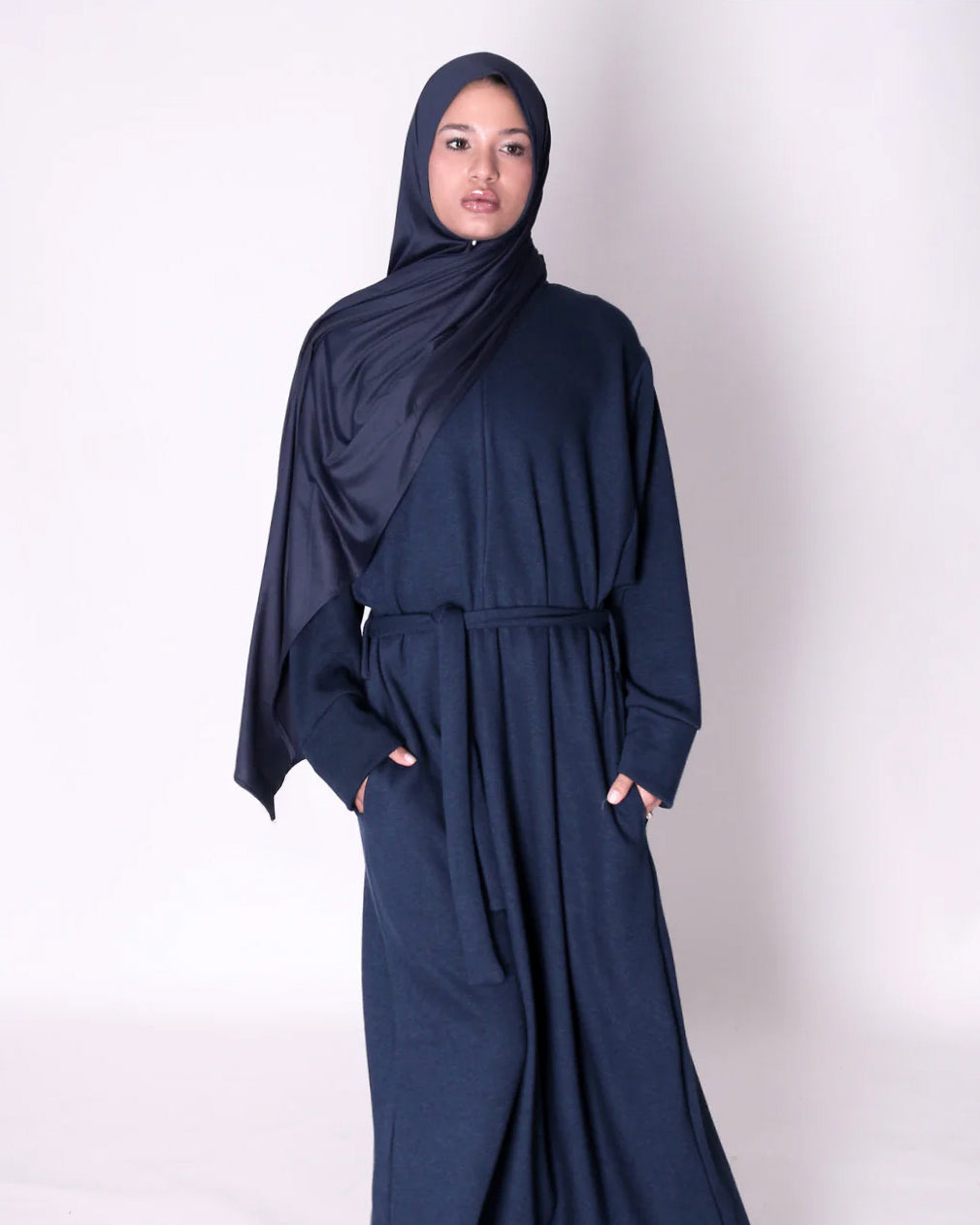 Woman wearing a navy blue abaya dress on a white background