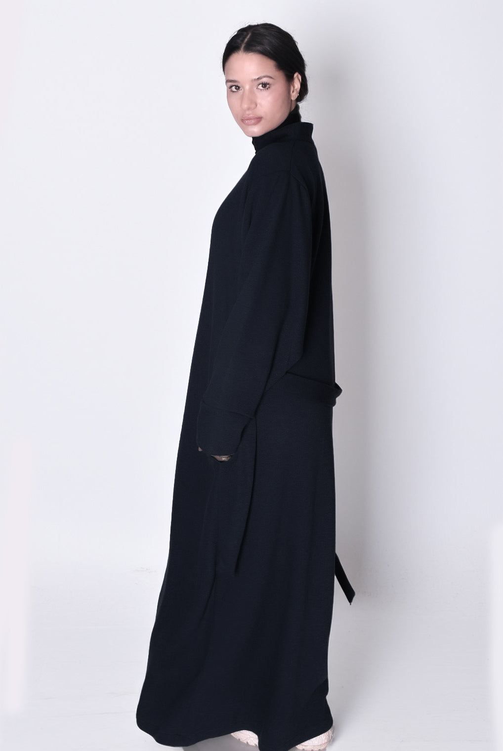 Woman wearing a long black dress against a white background. knitted abaya