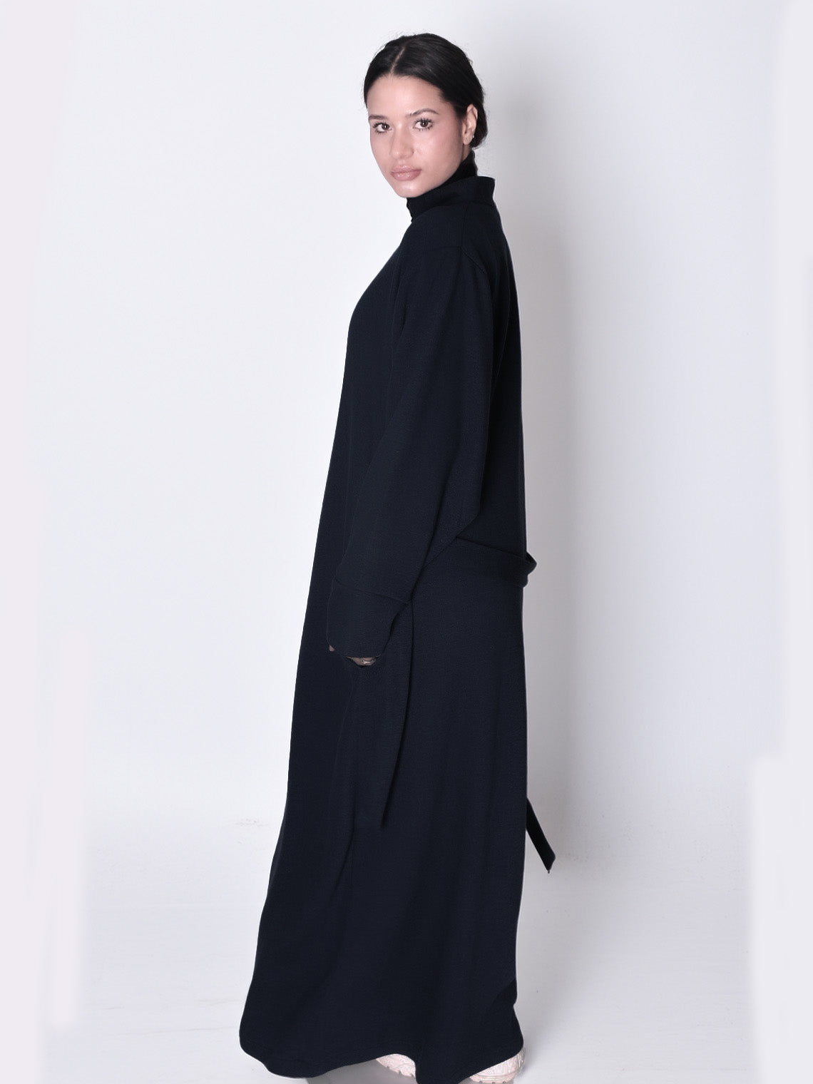 Woman wearing a long black dress against a white background. knitted abaya