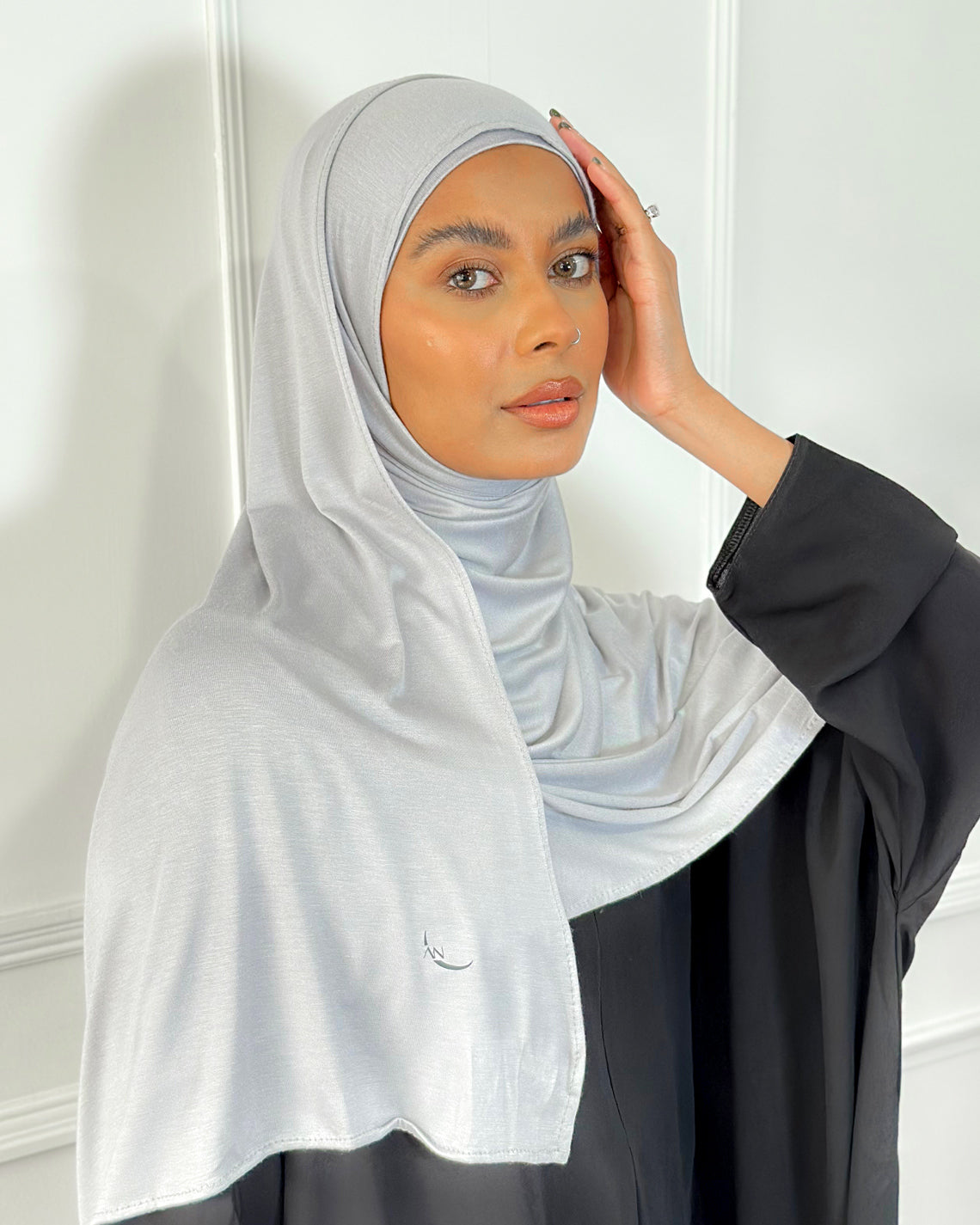 A woman wearing a light grey modal jersey hijab with a plain background. Modal Jersey Hijab