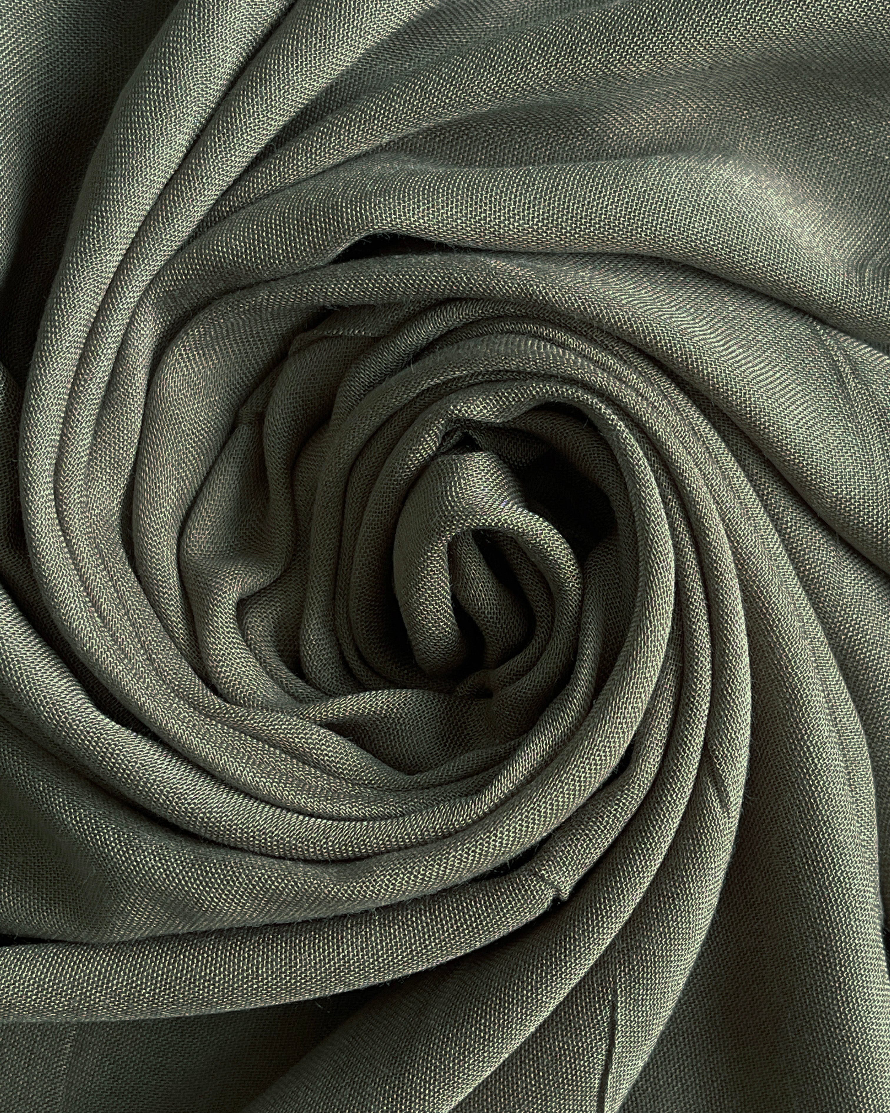 Rolled-up green fabric with a textured surface. olive modal hijab