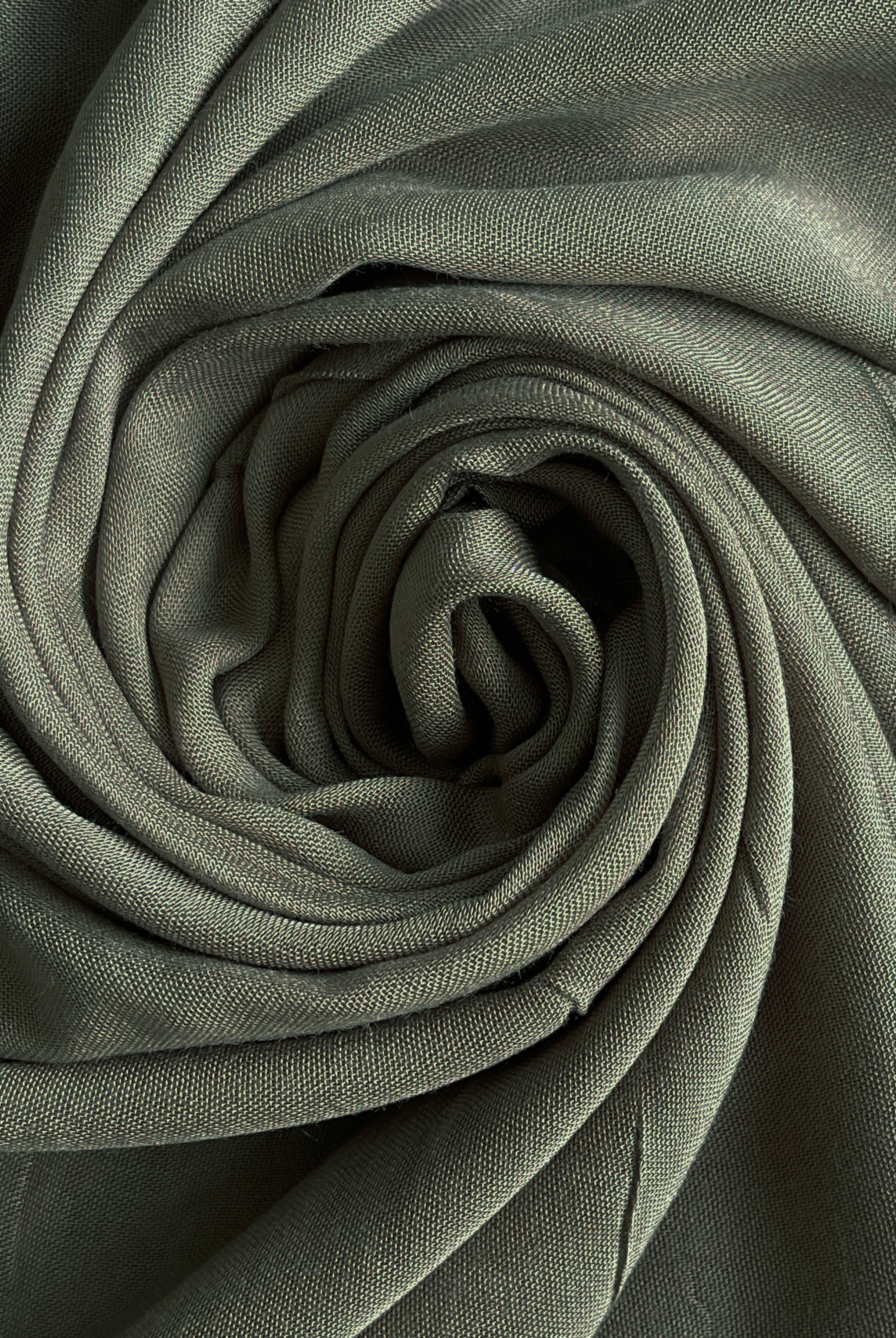 Rolled-up green fabric with a textured surface. olive modal hijab