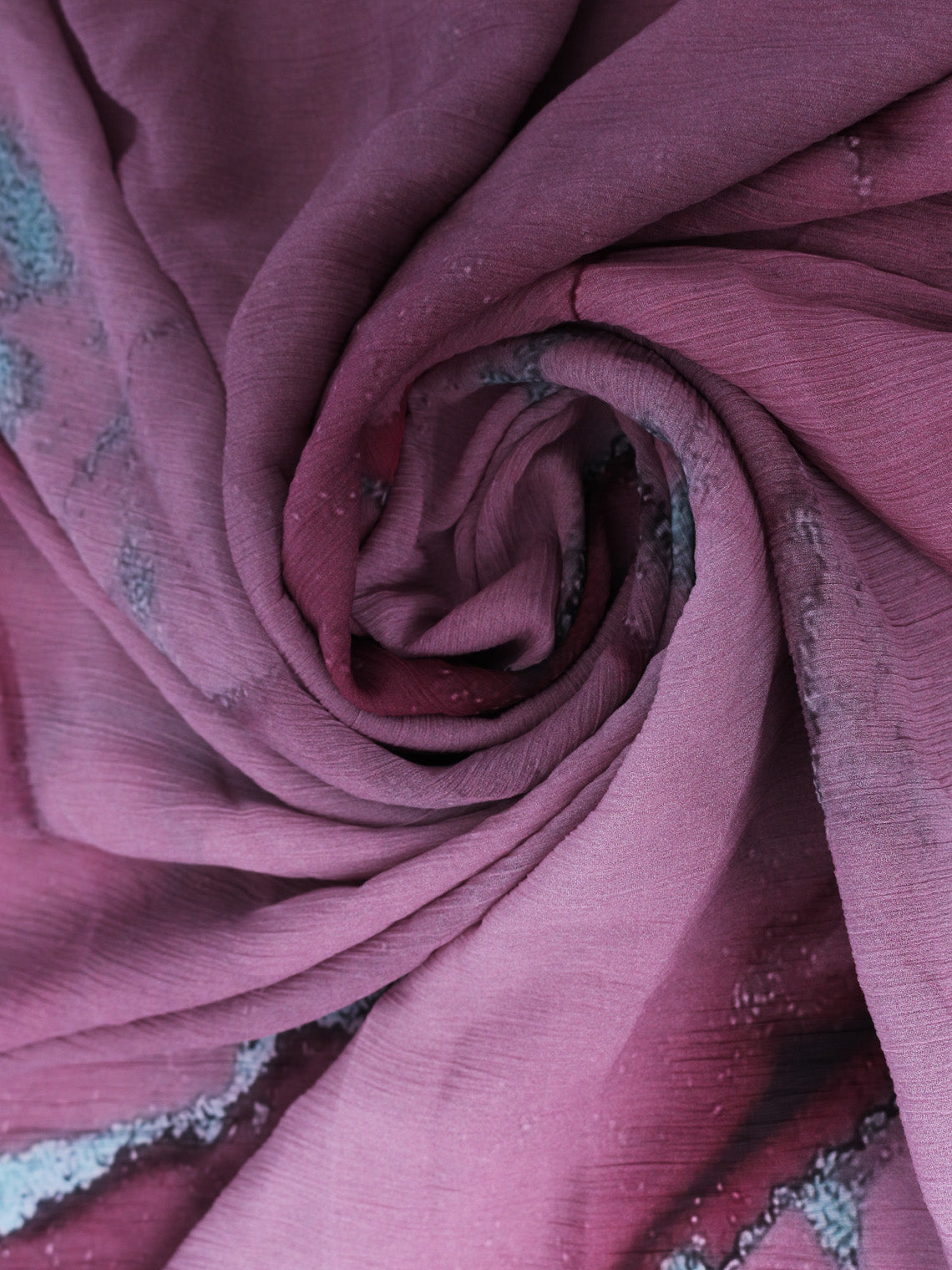 A pink chiffon scarf with a floral pattern and a twisted, swirling shape.
