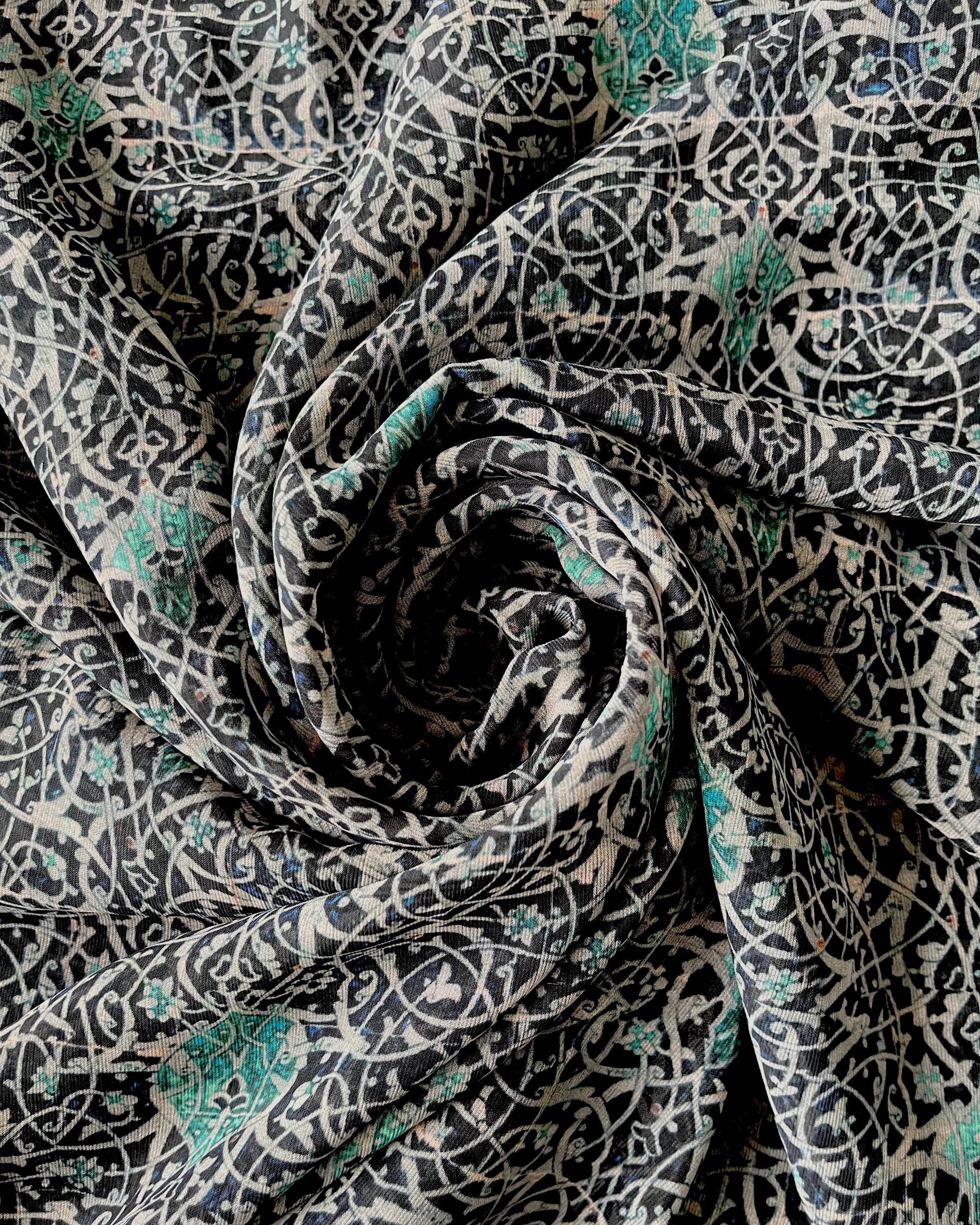 A close-up view of a blue and white swirl print hijab, showcasing the delicate pattern and fabric texture.