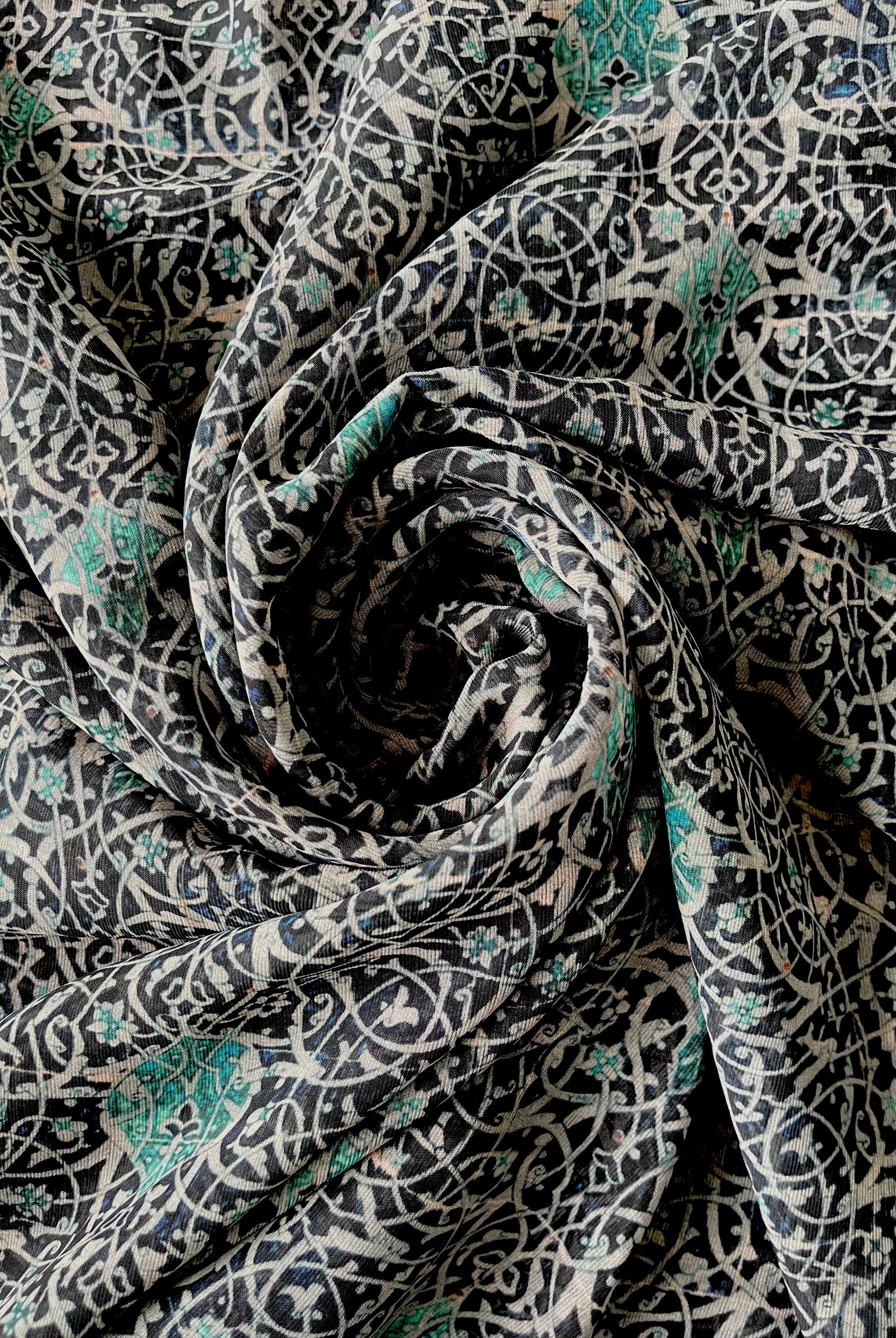 A close-up view of a blue and white swirl print hijab, showcasing the delicate pattern and fabric texture.