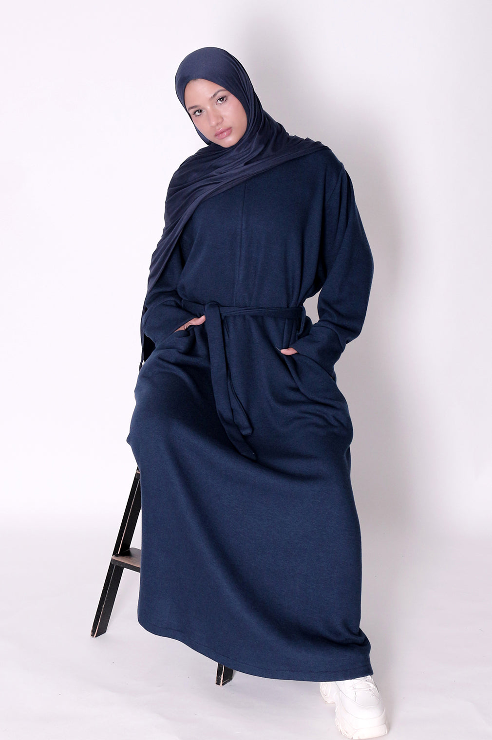 Woman wearing a navy blue abaya and hijab on a white background