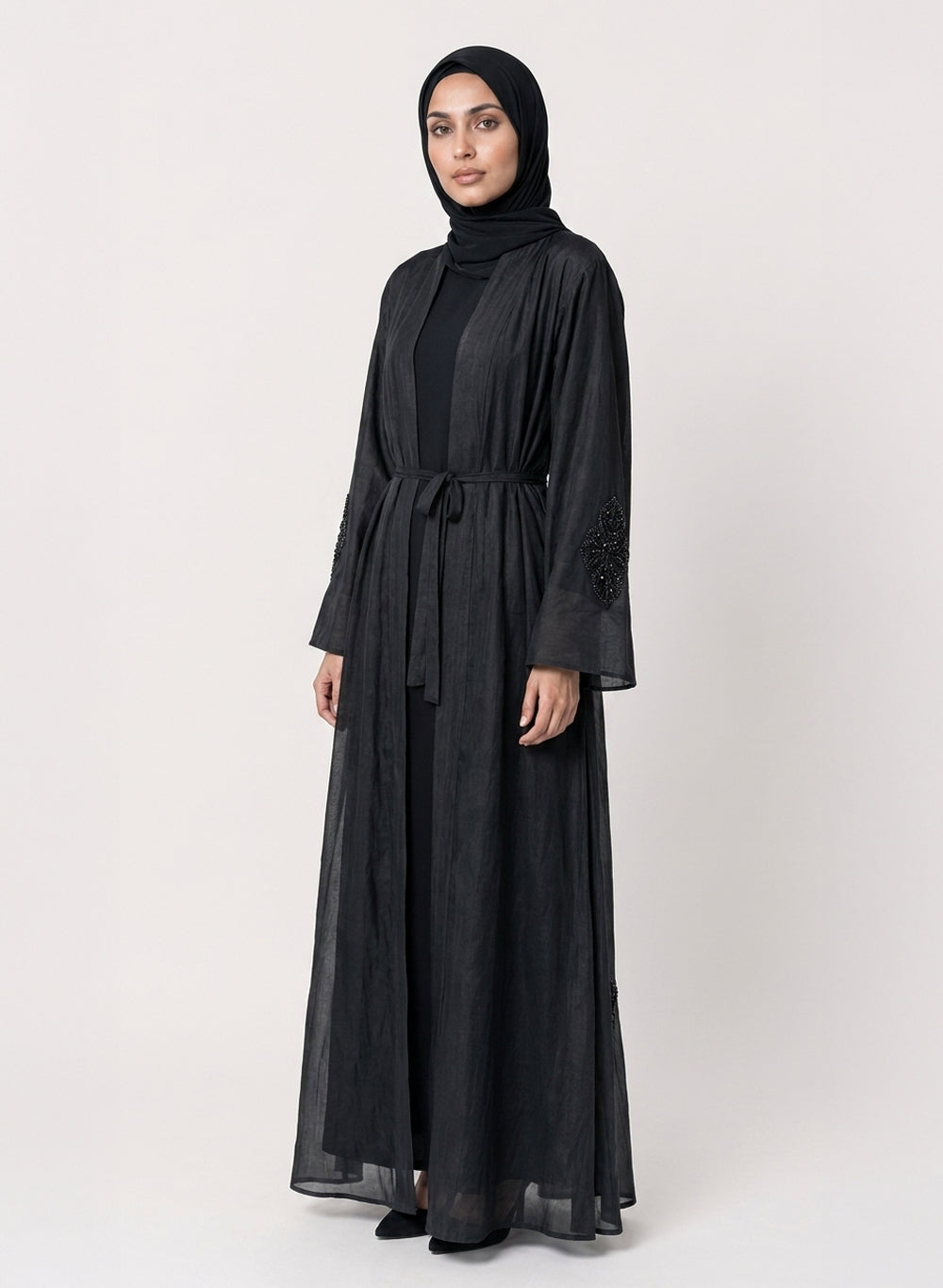 Black silk cotton Persia jacket with handcrafted embellishment, worn open over a matching black slip dress.