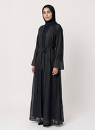 Black silk cotton Persia jacket with handcrafted embellishment, worn open over a matching black slip dress.