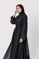 Black silk cotton Persia jacket with handcrafted embellishment, worn open over a matching black slip dress.