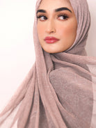 Woman wearing a pink calligraphy hijab against a light background