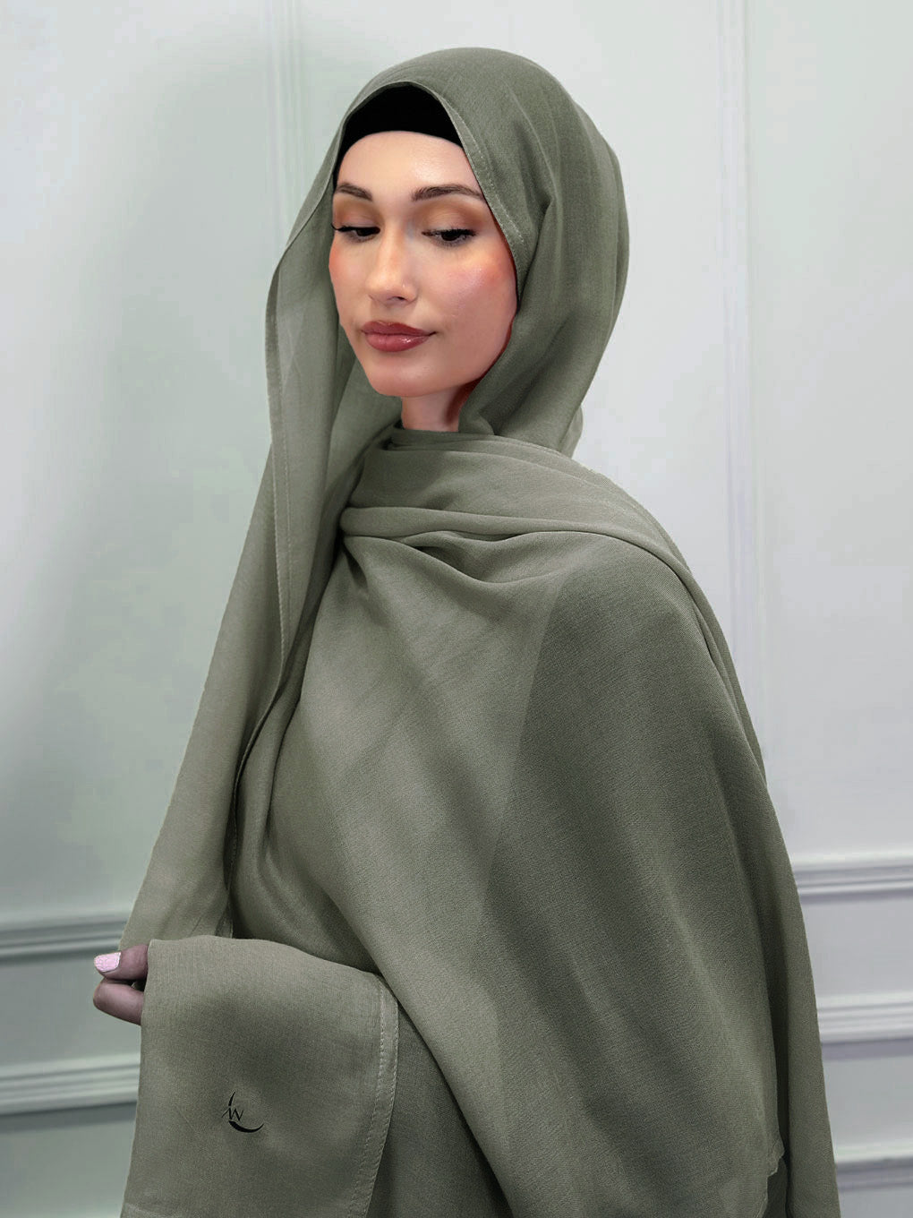Woman wearing a green hijab against a plain background. olive modal hijab