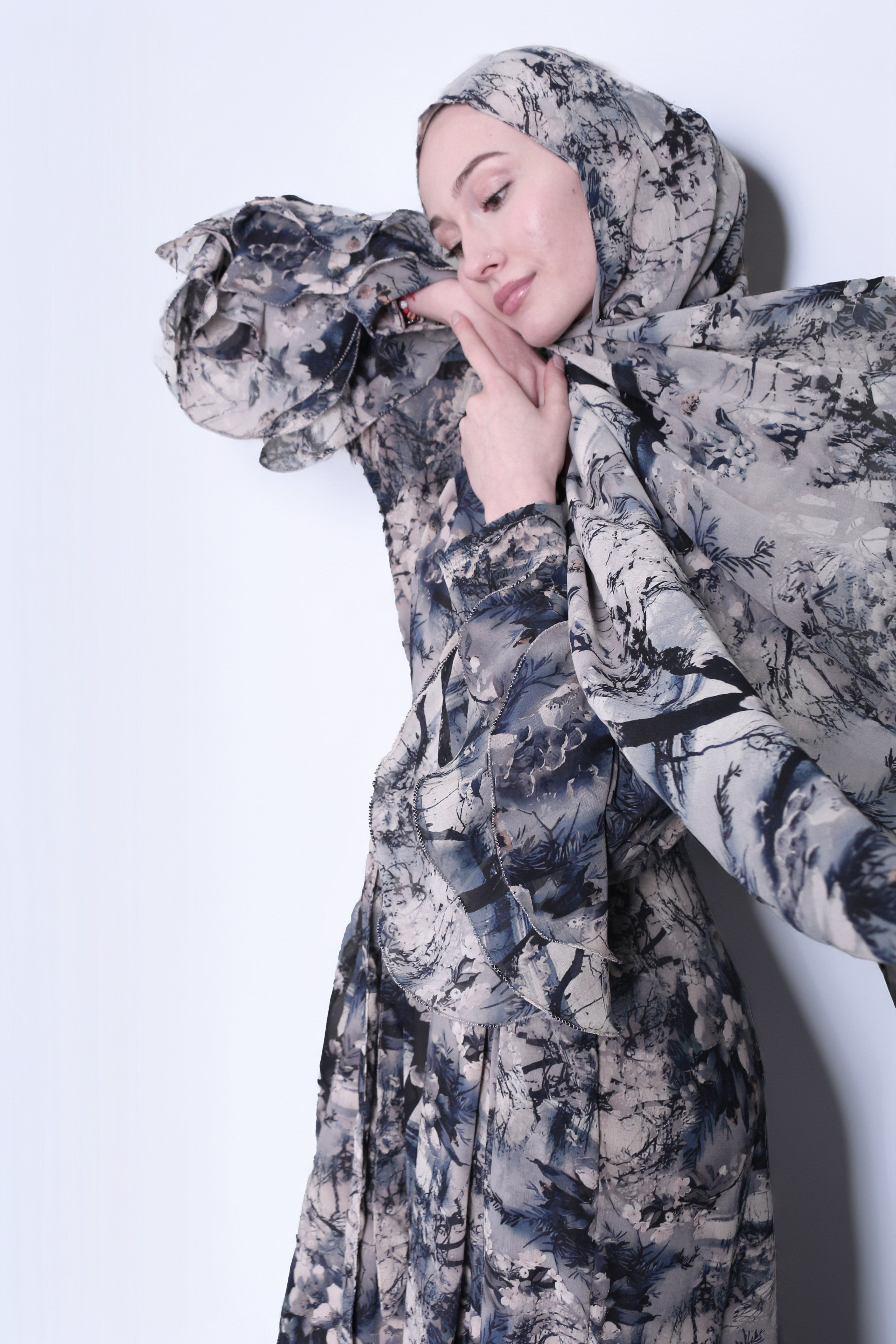 A woman wearing a Kyoto print hijab with a floral pattern in shades of gray and blue.