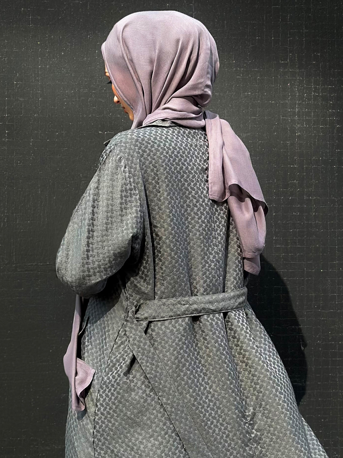 Person wearing a khafiyah coat and maxi jersey hijab against a dark background