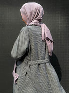 Person wearing a khafiyah coat and maxi jersey hijab against a dark background