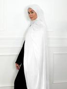 Woman wearing a white hijab and black outfit against a white wall ideal for umrah