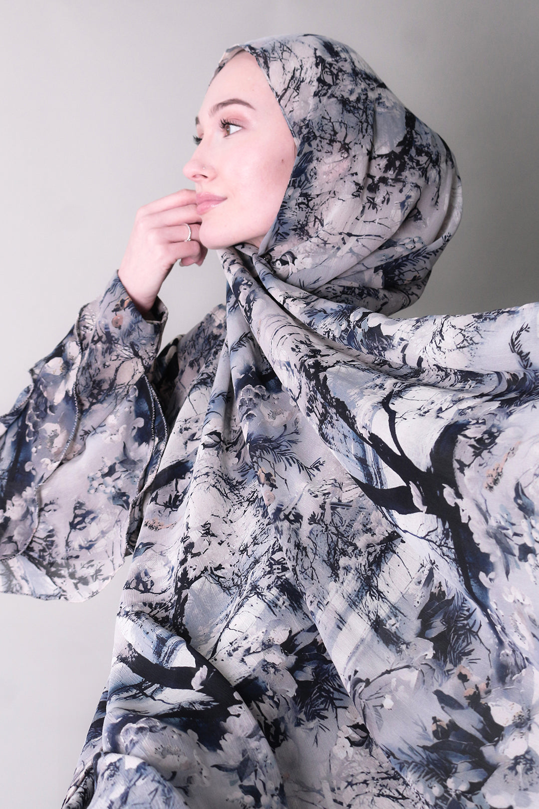 A woman wearing a blue and white chiffon hijab with a floral pattern printed scarves