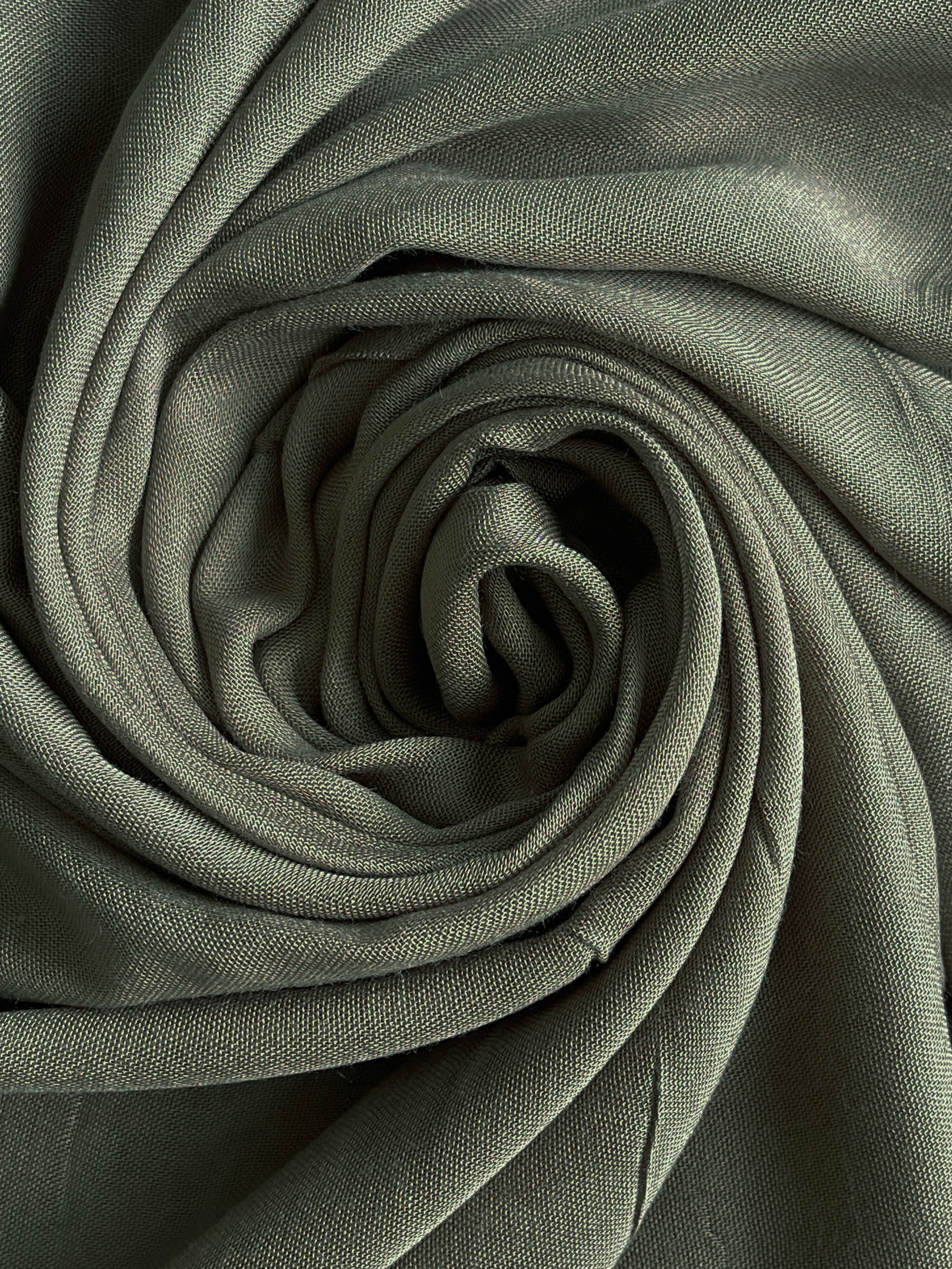 Rolled-up green fabric with a textured surface. olive modal hijab