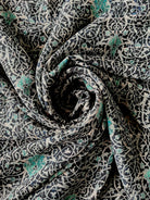 A close-up view of a blue and white swirl print hijab, showcasing the delicate pattern and fabric texture.